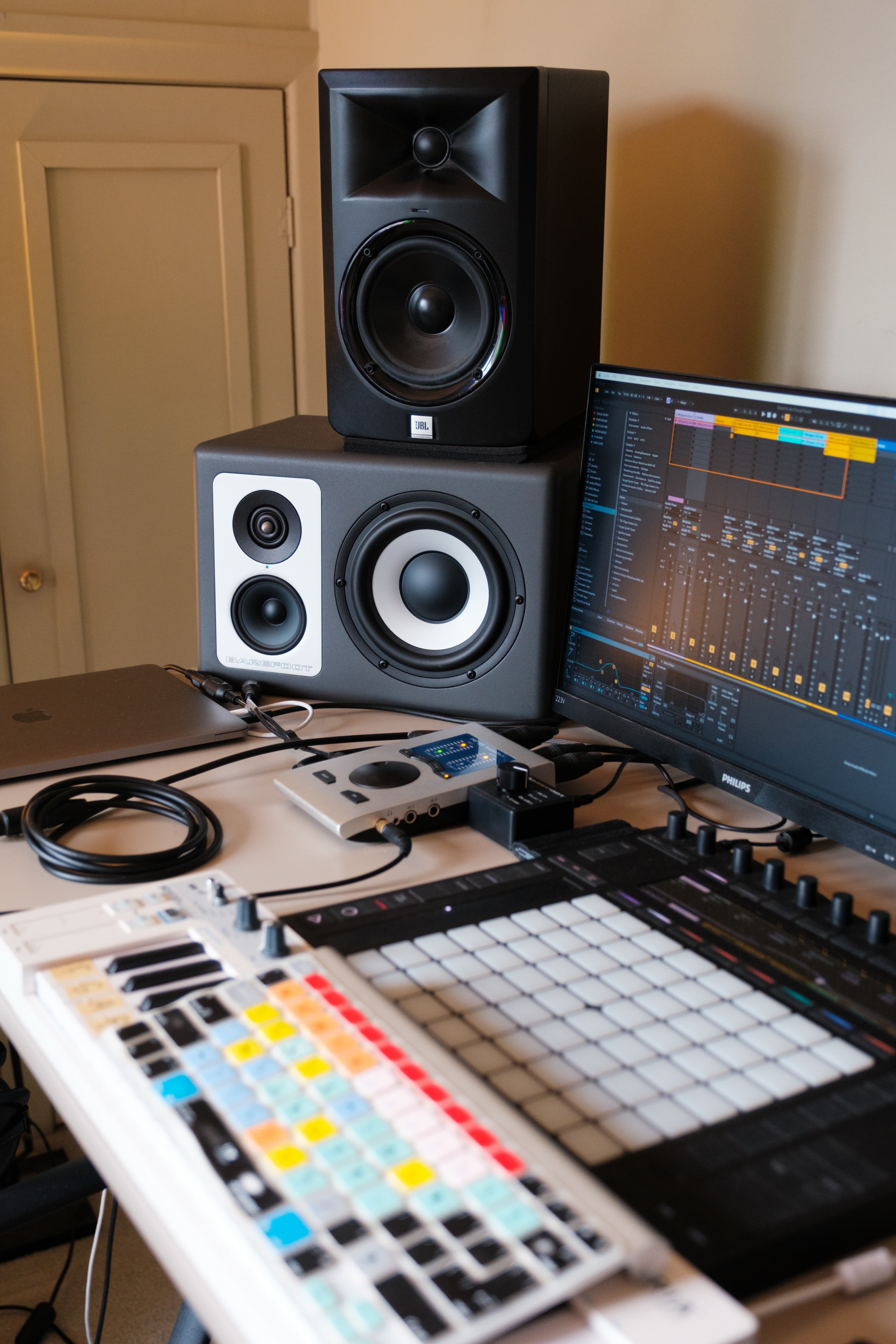 Home studio desk with JBL and Barefoot studio monitors, a laptop, and Ableton Live open on a screen