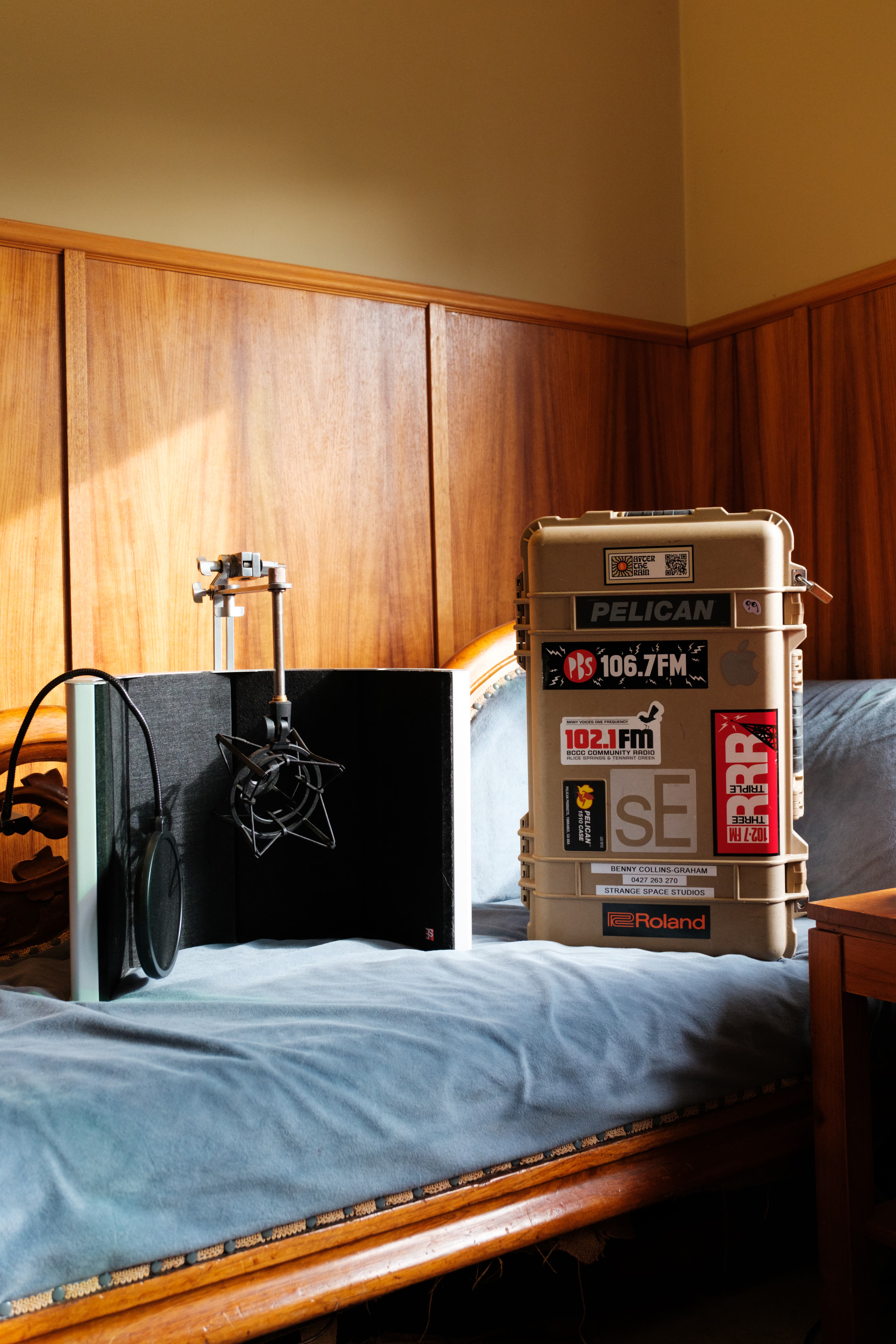 Condenser microphone on a stand beside a road case covered in radio station stickers